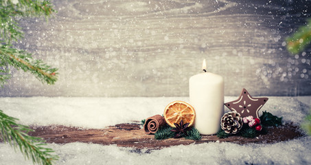 burning candle from advent in front of vintage background and decorative christmas background in...