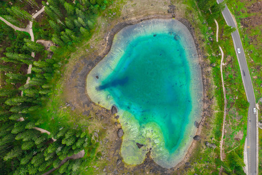 Aerial view of turquoise blue water of lake Carezza in Alps Dolomites. Lago di Karersee near fir tree forest.