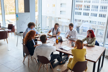 creative and enthusiastic business group sitting in office together working as team, wearing formal...