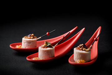 Goose liver pate, foie gras, served on black stone in Japanese red spoons. Paste served with jam...