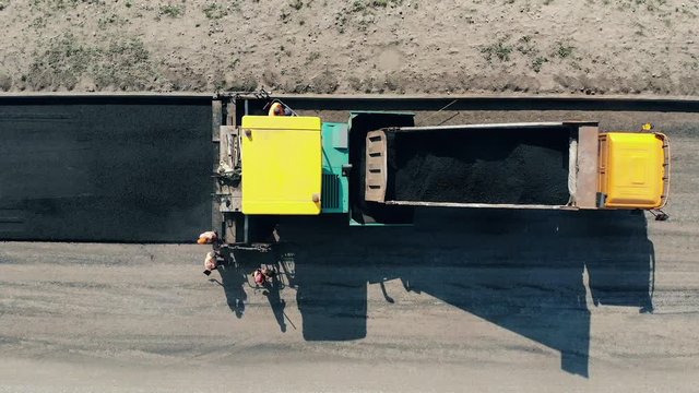 Construction workers working on a road construction. Bitum is being spread onto the road by the workers