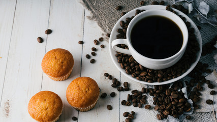 Close up still life, cup of coffee with muffins. Freshly baked delicious muffins and cup of coffee on wooden table. Cup of fresh aromatic coffee and cupcake at table in cafe.