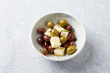 Green and kalamata olives, capers and feta cheese on bright stone background. Healthy Snack Idea. Close up. Copy space. 