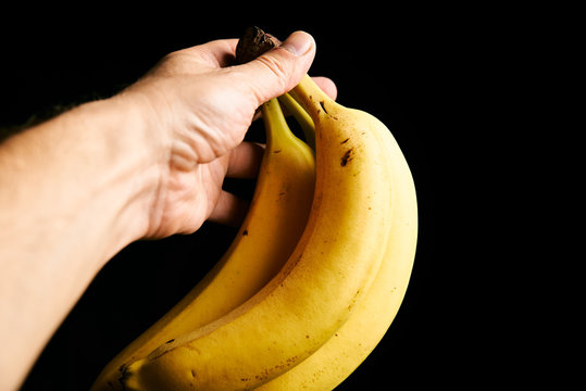 Fresh yellow babanas in the man hand isolated on black background with copyspase for cards and design for healthy life.