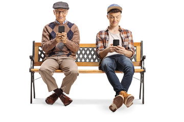 Elderly man and a young guy sitting on a bench and using mobile phones