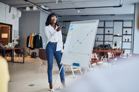 black businesswoman stand talking explaining making flip chart presentation for office employees using diagrams, motivated african American speaker coach present business plan - Powered by Adobe