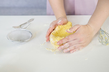 Obraz na płótnie Canvas Woman's hands knead dough on a white table