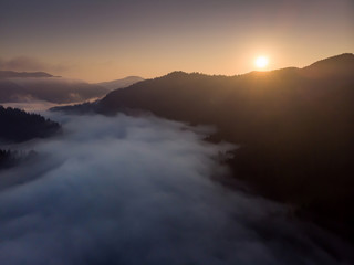 silhouettes of mountains and fog at sunrise