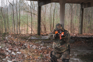 Military man with Kalashnikov rifle outdoor forest