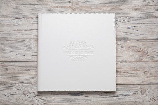 family photo book with white fabric cover. white wedding photo album on a wooden background with space for text white photobook close up. photoalbum  with a beautiful stylish cover