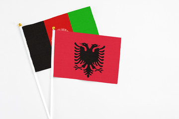 Albania and Afghanistan stick flags on white background. High quality fabric, miniature national flag. Peaceful global concept.White floor for copy space.