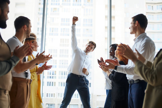 Happy business team is clapping their hands in modern workstation, celebrating the performance of new product of their man colleague working together
