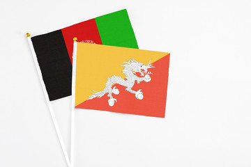 Bhutan and Afghanistan stick flags on white background. High quality fabric, miniature national flag. Peaceful global concept.White floor for copy space.