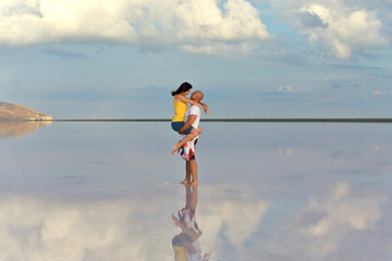 A young couple in love embrace in the middle of a salt lake at sunset.