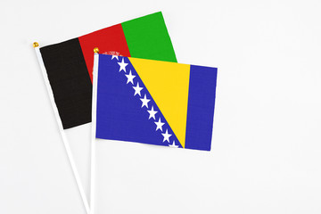Bosnia Herzegovina and Afghanistan stick flags on white background. High quality fabric, miniature national flag. Peaceful global concept.White floor for copy space.