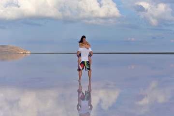 A young couple in love embrace in the middle of a salt lake at sunset.