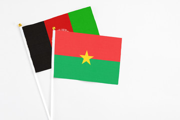 Burkina Faso and Afghanistan stick flags on white background. High quality fabric, miniature national flag. Peaceful global concept.White floor for copy space.