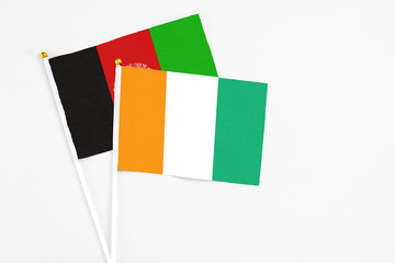 Obraz premium Cote D'Ivoire and Afghanistan stick flags on white background. High quality fabric, miniature national flag. Peaceful global concept.White floor for copy space.