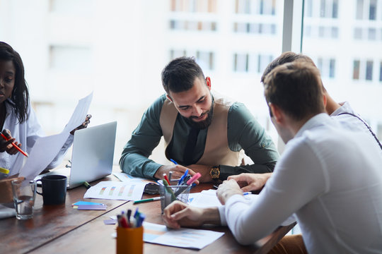 Executives having friendly discussion during break, business ideas, building business strategy while sititng on table together . office background