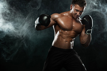 Boxer, man fighting or posing in gloves on black background. Fitness and boxing concept. Individual...