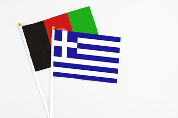 Obraz premium Greece and Afghanistan stick flags on white background. High quality fabric, miniature national flag. Peaceful global concept.White floor for copy space.