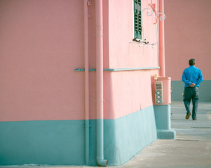 Fototapeta na wymiar homme en bleu dans une rue rose