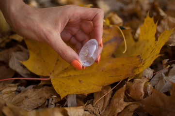 Female hand with orange manicure holding transparent violet amethyst yoni egg for vumfit,...