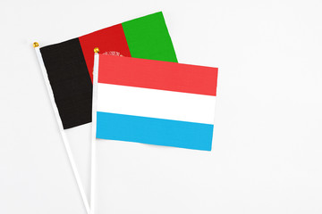 Luxembourg and Afghanistan stick flags on white background. High quality fabric, miniature national flag. Peaceful global concept.White floor for copy space.