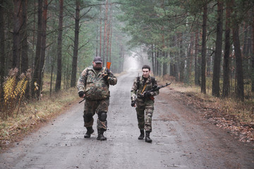 Fototapeta premium two Russian soldiers in military clothes and weapons move through the forest