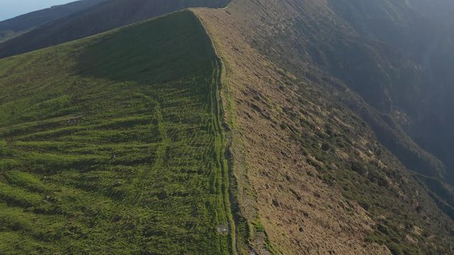 Trail around the huge caldera on the top of green inactive volcano. Aerial of Faial, Azores