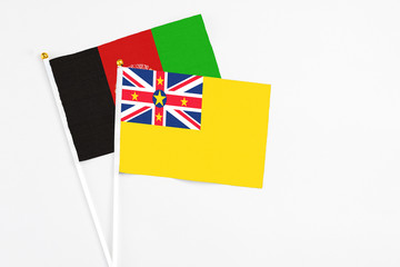 Niue and Afghanistan stick flags on white background. High quality fabric, miniature national flag. Peaceful global concept.White floor for copy space.