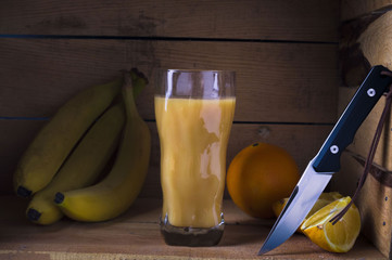 Multivitamin juice with fruits. Citrus juice. Juice from bananas and oranges. Knife and fruits.
