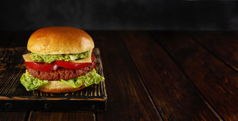 Homemade vegetarian burger on wooden board on dark background