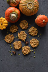 Vegan gluten free baking concept. Flatlay of breakfast homemade oatmeal cookies and winter squashes on black background