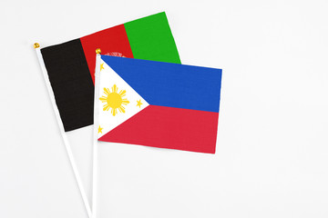 Philippines and Afghanistan stick flags on white background. High quality fabric, miniature national flag. Peaceful global concept.White floor for copy space.