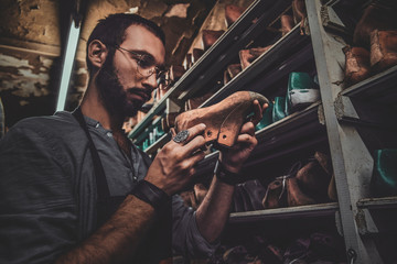 Bearded cobbler in glasses found the right shoe form for his new collection.
