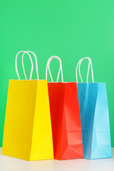 Colorful shopping or gift bags on wooden desk against green background. The concept of shopping or gifts. Layout with a copy space for your ideas.