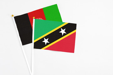 Saint Kitts And Nevis and Afghanistan stick flags on white background. High quality fabric, miniature national flag. Peaceful global concept.White floor for copy space.