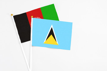 Saint Lucia and Afghanistan stick flags on white background. High quality fabric, miniature national flag. Peaceful global concept.White floor for copy space.