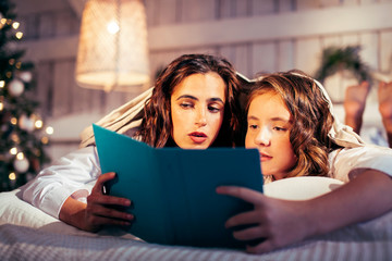 young pretty girls in bed at Christmass morning, happy family smiling lifestyle at holiday reading book