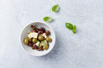 Green and kalamata olives, capers and feta cheese on bright stone background. Healthy Snack Idea. Top view. Copy space. 