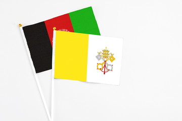 Vatican City and Afghanistan stick flags on white background. High quality fabric, miniature national flag. Peaceful global concept.White floor for copy space.