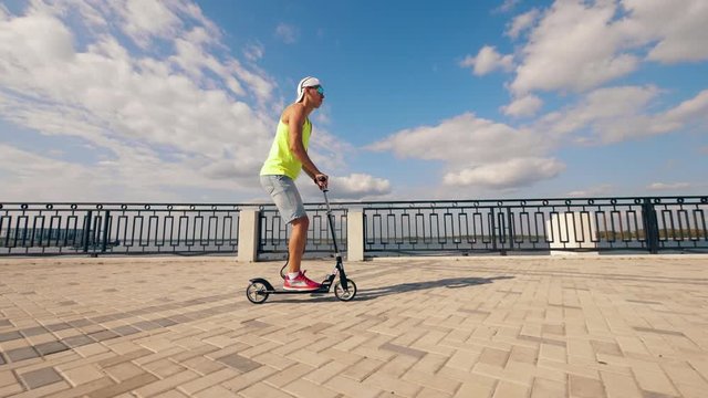Slow motion of a handicapped man riding a scooter along the quay