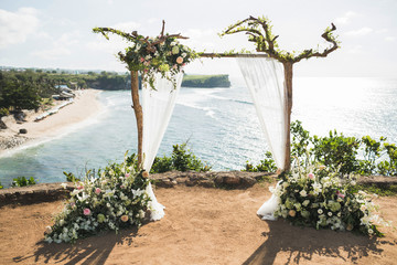 Sunset wedding ceremony arch with wooden branches and flower decoration and white cloth canopy....