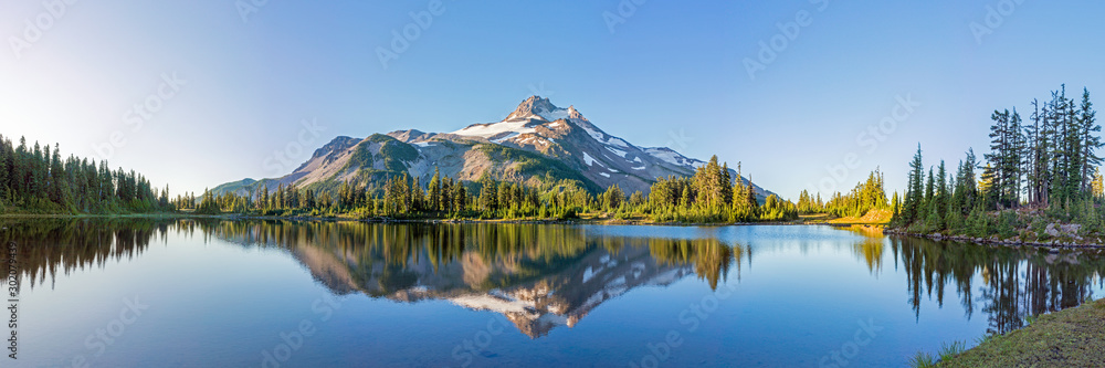 Wall mural volcanic mountain in morning light reflected in calm waters of lake.