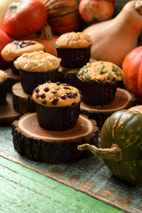 Healthy homemade sweets concept. Imperfect pumpkin muffins with seeds and chocolate on wood slabs on shabby green wooden background side view copy space. Low key still life