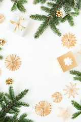 Christmas / New Year holiday composition. Frame of fir branches, gift boxes, straw decorations on white background. Flat lay, top view festive copy space mockup.