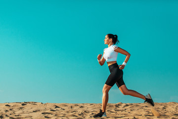 Sporty young woman and fit athlete runner running on the sky background. The concept of a healthy...