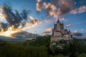 Naklejka premium Castle at the top of the mountain, surrounded by forest is illuminated by the first rays of the sun in the morning.