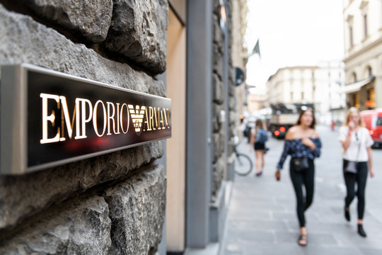 Florence, Italy - August 31, 2018: Italian Emporio Armani boutique, fashion clothing store in Firenze, sign, entrance, old stone architecture with people, women, woman walking on street, sidewalk